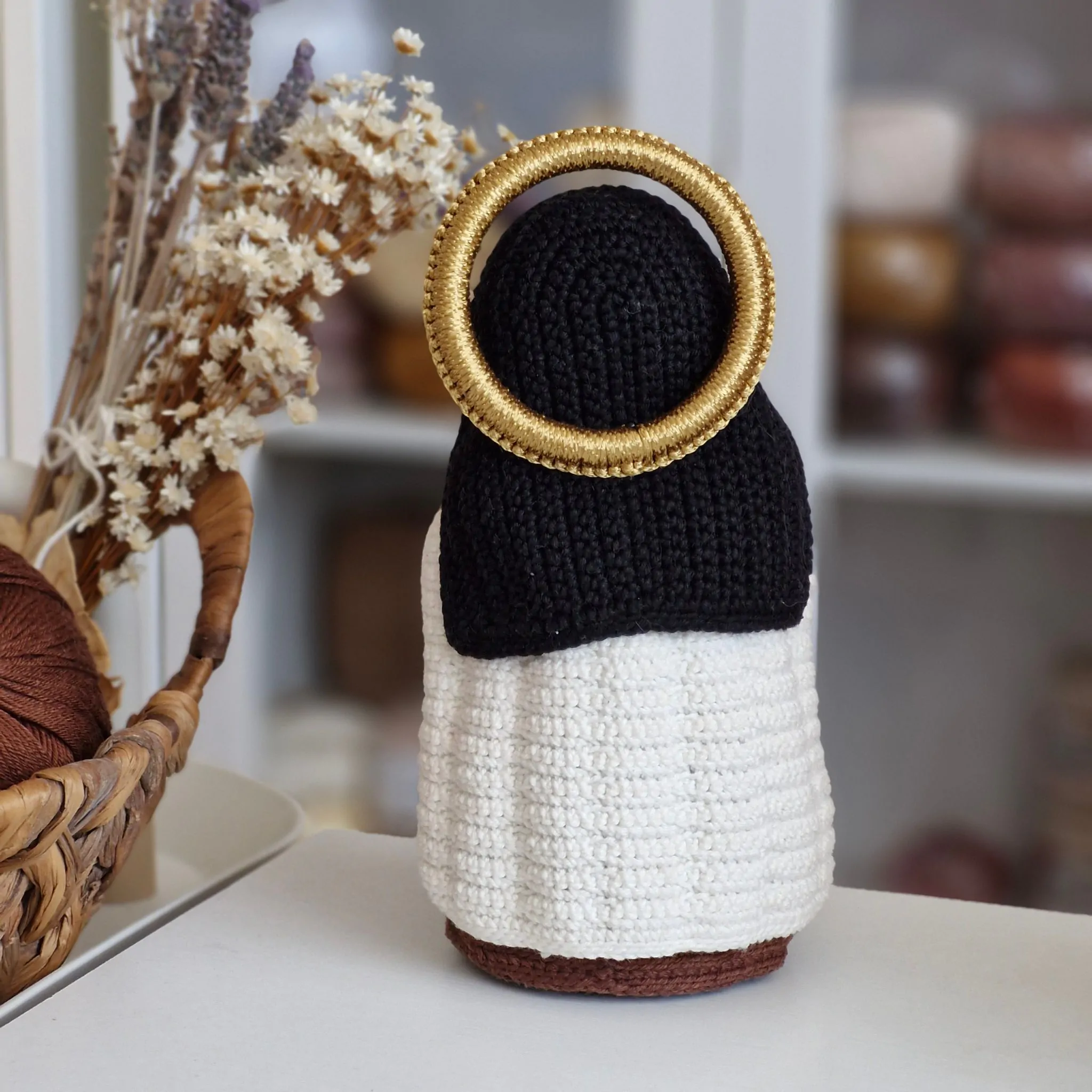 Vista traseira da Santa Teresinha do Menino Jesus em amigurumi mostrando o véu, o manto carmelita e o halo dourado.