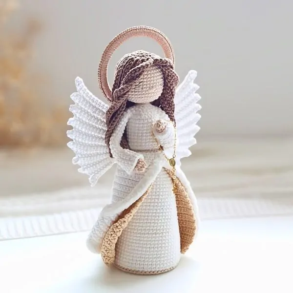 Anjo em amigurumi com asas brancas, auréola e rosário em crochê artesanal