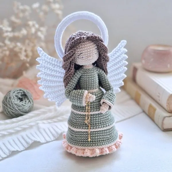 Anjo em amigurumi com rosário, asas brancas e veste verde em crochê artesanal
